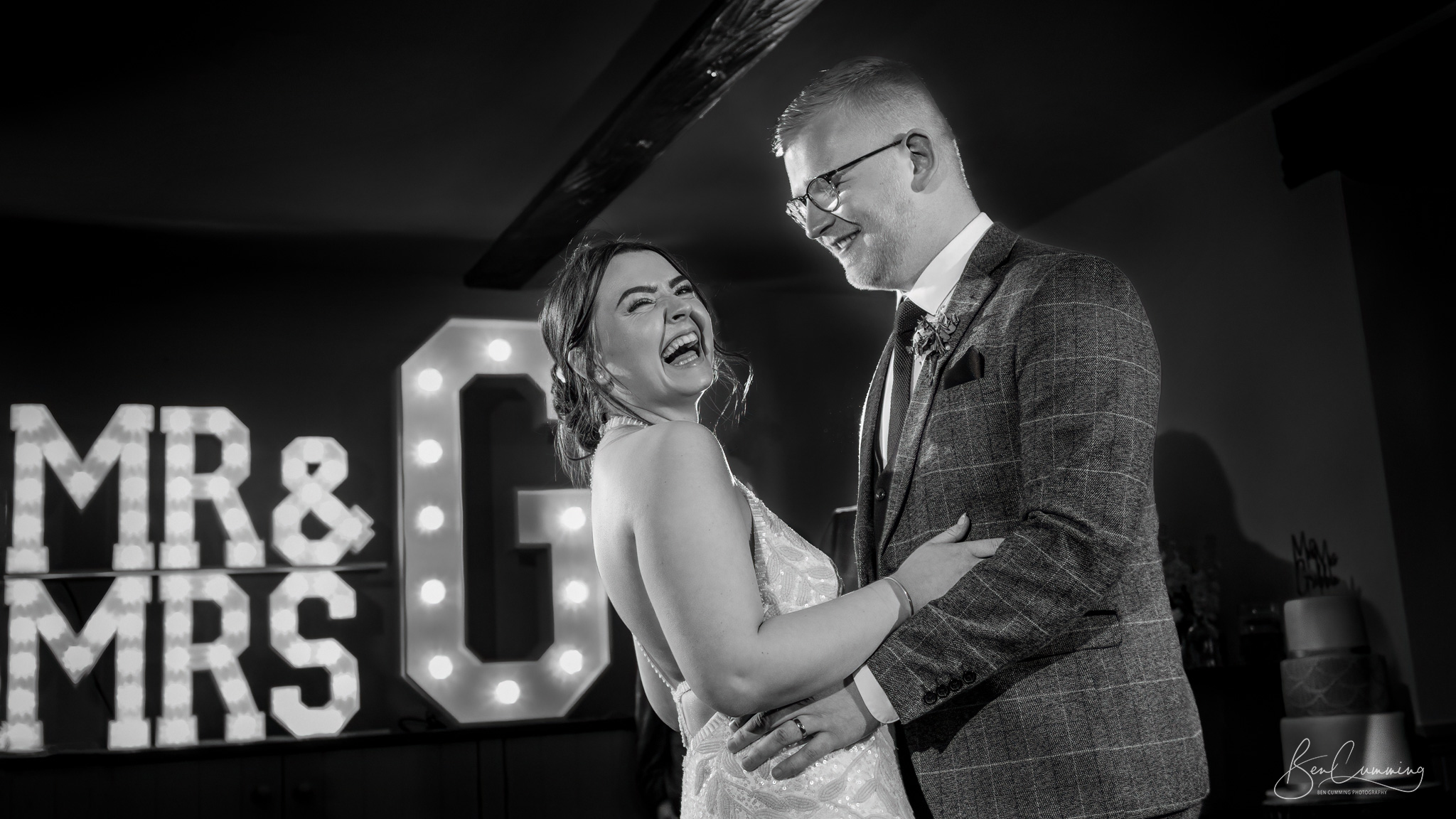 A bride and groom standing in front of a mr and mrs sign.