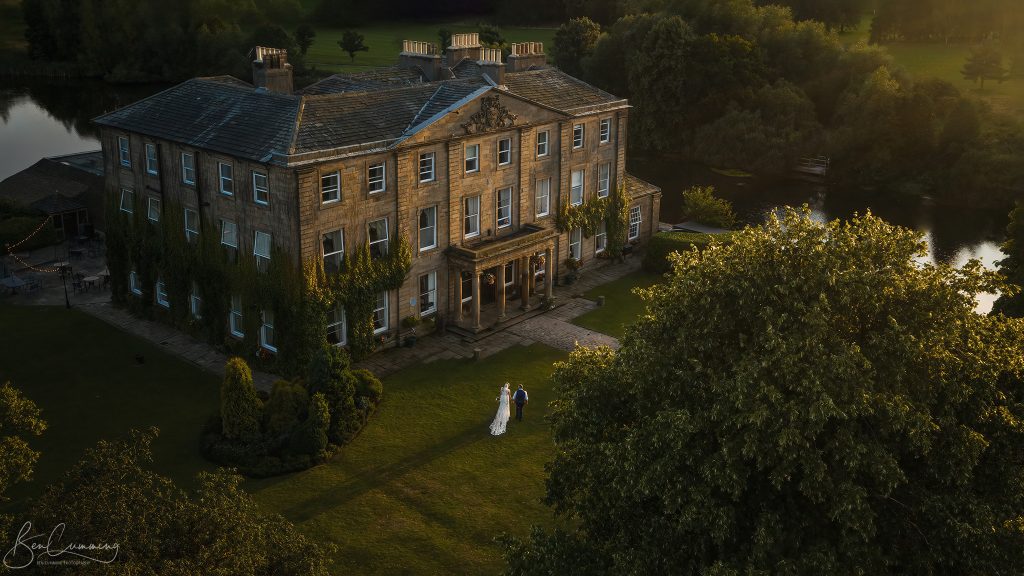Bride and Groom Drone Photograph of them Walking outside Waterton Park in the sun